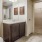 Large well lit bathroom with large mirror and brown cabinets 